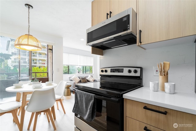 kitchen featuring decorative light fixtures, light brown cabinetry, and appliances with stainless steel finishes