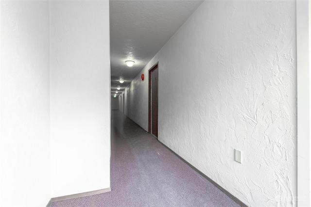 corridor featuring carpet flooring and a textured ceiling