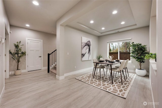 dining room featuring a tray ceiling and light hardwood / wood-style flooring