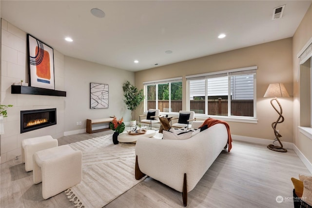 living room with a tile fireplace and light wood-type flooring