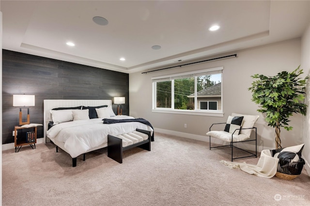 bedroom featuring wooden walls, a raised ceiling, and light carpet