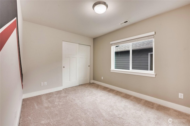 unfurnished bedroom with a closet and light colored carpet