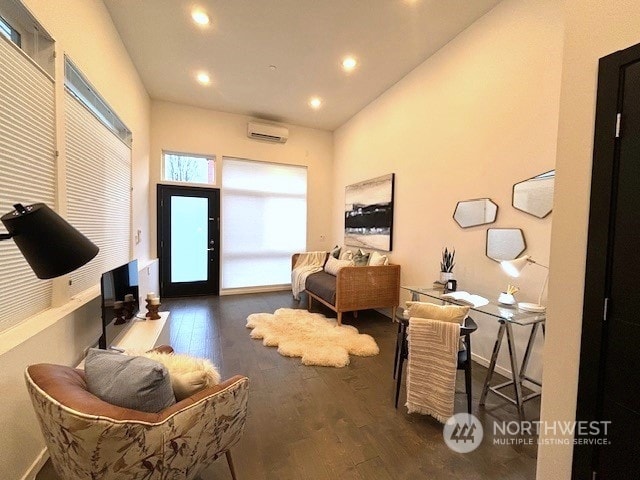 living area featuring a wall unit AC and dark wood-type flooring