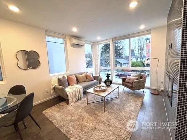 living room with a wall unit AC and dark hardwood / wood-style floors