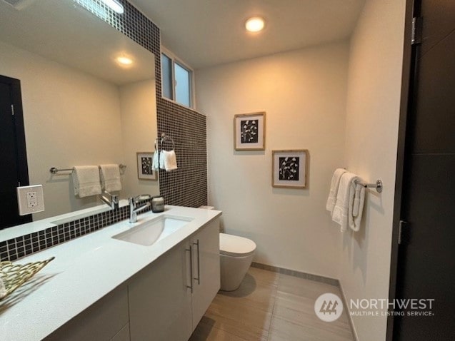 bathroom featuring decorative backsplash, tile patterned floors, vanity, and toilet