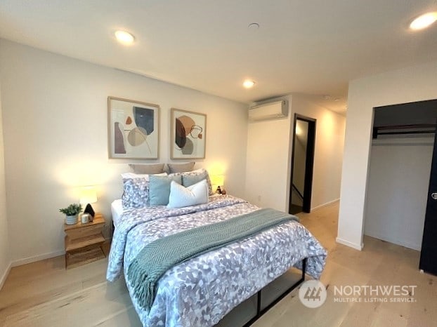 bedroom with light wood-type flooring and a wall unit AC