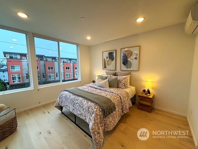 bedroom featuring light hardwood / wood-style floors and a wall mounted AC