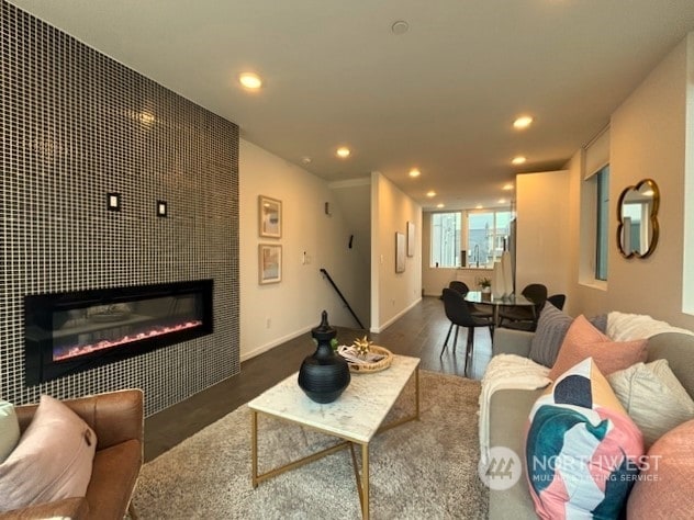 living room with a tile fireplace and dark hardwood / wood-style floors