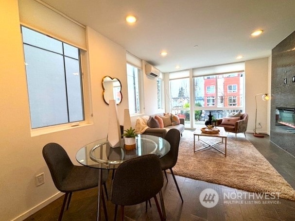 dining space featuring a wall mounted AC and a fireplace