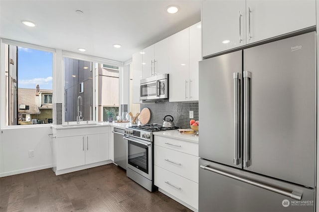 kitchen featuring white cabinetry, dark hardwood / wood-style flooring, stainless steel appliances, tasteful backsplash, and sink