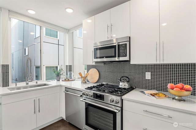 kitchen featuring decorative backsplash, sink, white cabinetry, and appliances with stainless steel finishes