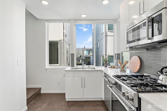 kitchen with white cabinets, dark hardwood / wood-style floors, appliances with stainless steel finishes, and tasteful backsplash