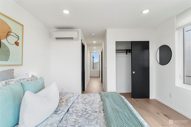 bedroom featuring an AC wall unit, a closet, and light wood-type flooring