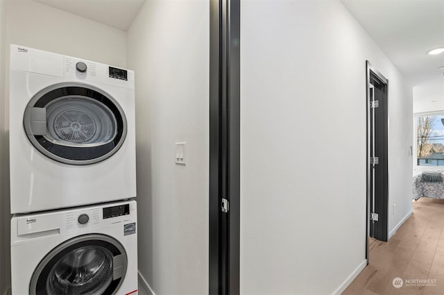 washroom featuring stacked washer / drying machine and light hardwood / wood-style floors