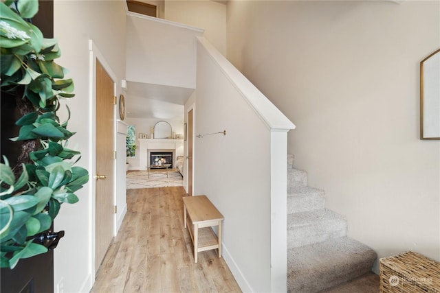 stairs with a high ceiling, hardwood / wood-style flooring, and a fireplace