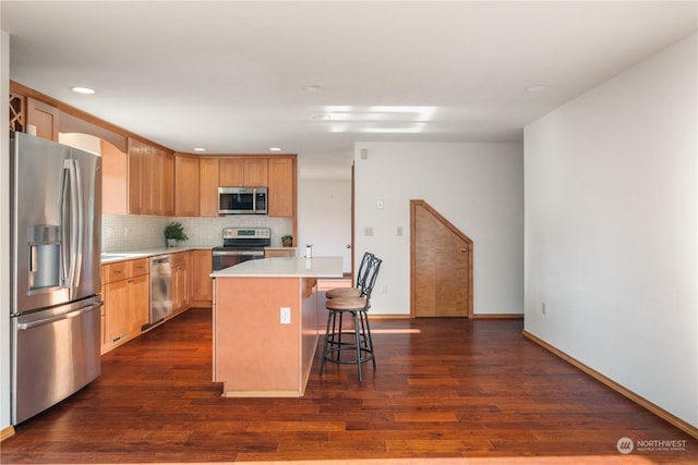 kitchen with stainless steel appliances, a center island, dark wood-type flooring, and a kitchen breakfast bar