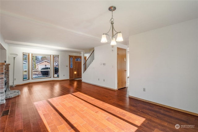 unfurnished living room with an inviting chandelier, wood-type flooring, and a fireplace