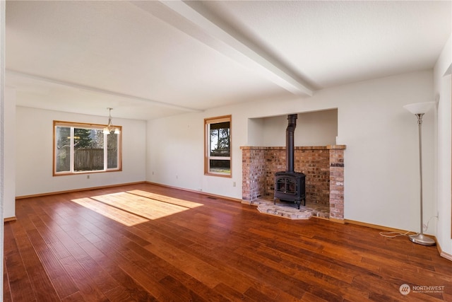 unfurnished living room featuring hardwood / wood-style flooring, a wood stove, and beam ceiling