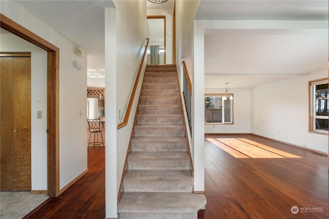 stairs featuring hardwood / wood-style floors and a notable chandelier