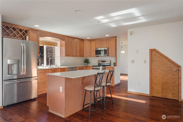 kitchen with dark hardwood / wood-style flooring, sink, stainless steel appliances, and a center island