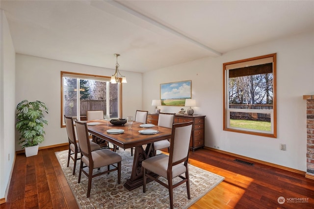 dining area with dark wood-type flooring, a healthy amount of sunlight, and a chandelier