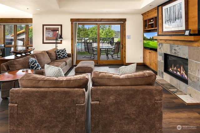 living room featuring dark hardwood / wood-style flooring, a healthy amount of sunlight, built in features, and a fireplace