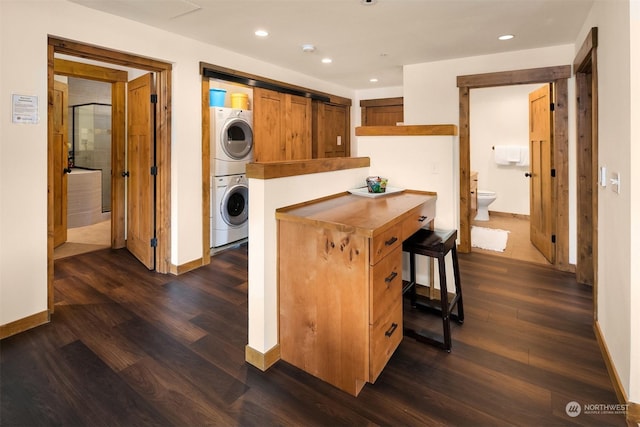 kitchen with a kitchen breakfast bar, dark hardwood / wood-style floors, kitchen peninsula, and stacked washer / dryer