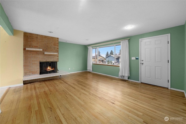 unfurnished living room featuring a textured ceiling, a fireplace, and hardwood / wood-style flooring