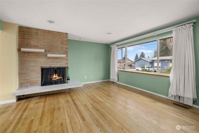 unfurnished living room with a brick fireplace and hardwood / wood-style flooring