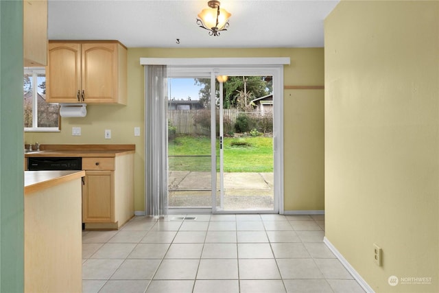 kitchen featuring light tile patterned flooring, light brown cabinetry, and dishwasher