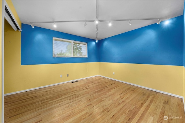 spare room with track lighting and light hardwood / wood-style flooring