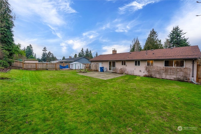 rear view of house with a lawn, a shed, and a patio area