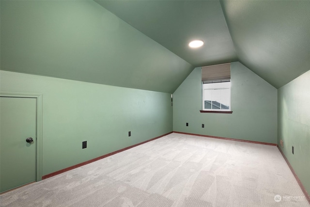 additional living space featuring lofted ceiling and light carpet