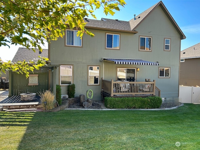 back of property featuring a wooden deck, an outdoor fire pit, and a lawn