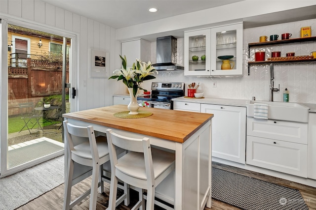 kitchen with electric range, light hardwood / wood-style floors, white cabinetry, and wall chimney exhaust hood