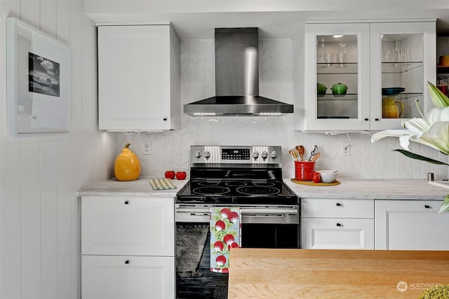 kitchen featuring white cabinets, stainless steel range with electric cooktop, wall chimney range hood, and tasteful backsplash