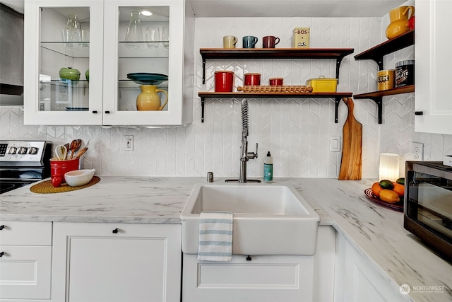 kitchen with light stone countertops, tasteful backsplash, white cabinets, stainless steel electric range oven, and sink