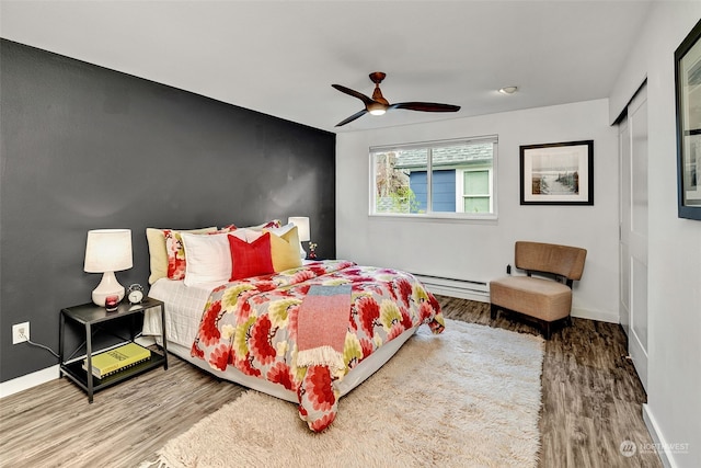 bedroom featuring ceiling fan, a baseboard radiator, and hardwood / wood-style flooring