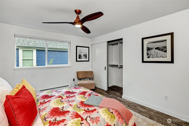 bedroom with a closet, a baseboard heating unit, ceiling fan, and dark hardwood / wood-style floors