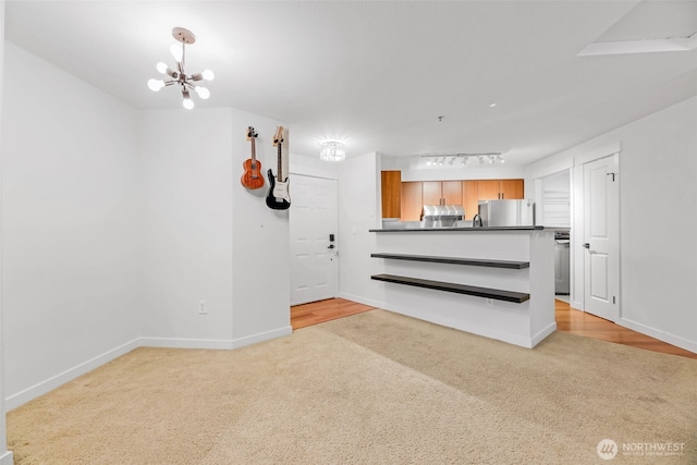 interior space featuring light carpet, an inviting chandelier, and baseboards