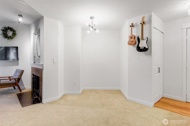 hall with a chandelier, carpet flooring, and baseboards