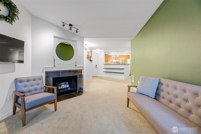 living room featuring track lighting, baseboards, carpet flooring, and a tiled fireplace