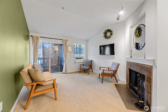 living area with lofted ceiling, carpet floors, a fireplace with flush hearth, and baseboards