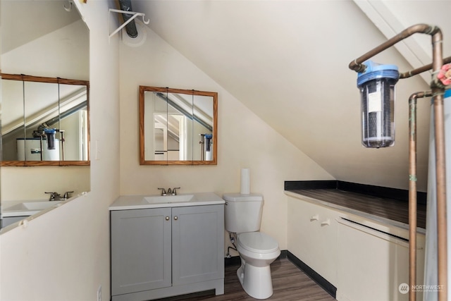 bathroom featuring vaulted ceiling, toilet, vanity, and hardwood / wood-style flooring