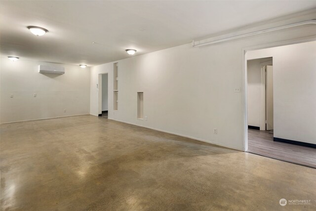 spare room featuring an AC wall unit and concrete floors