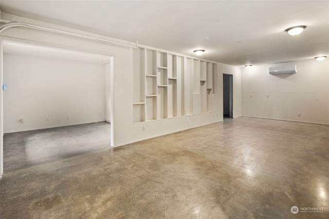 empty room featuring built in shelves, concrete flooring, and an AC wall unit