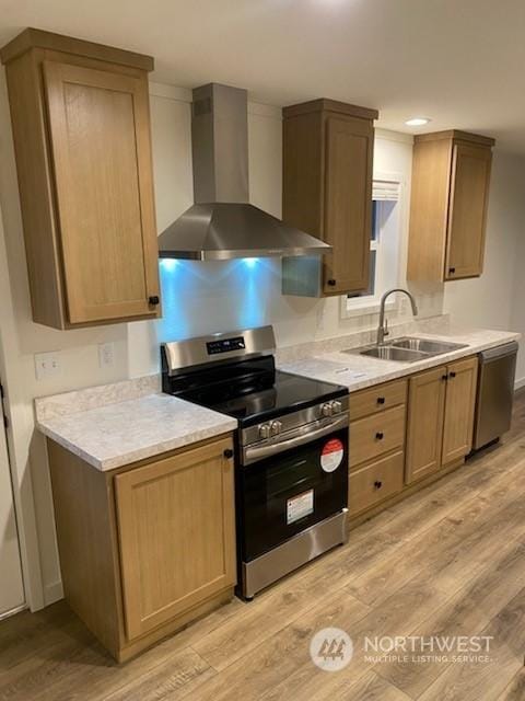 kitchen featuring sink, stainless steel appliances, light hardwood / wood-style flooring, and wall chimney exhaust hood