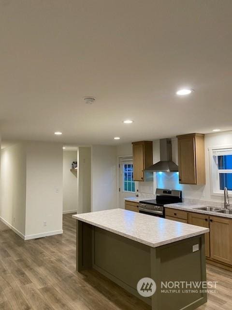 kitchen with wood-type flooring, a kitchen island, sink, stainless steel range with electric cooktop, and wall chimney range hood