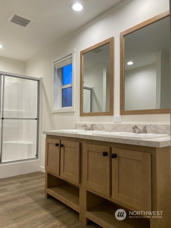 bathroom featuring an enclosed shower, vanity, and wood-type flooring