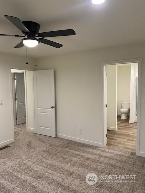 unfurnished bedroom with ensuite bathroom, ceiling fan, and light colored carpet